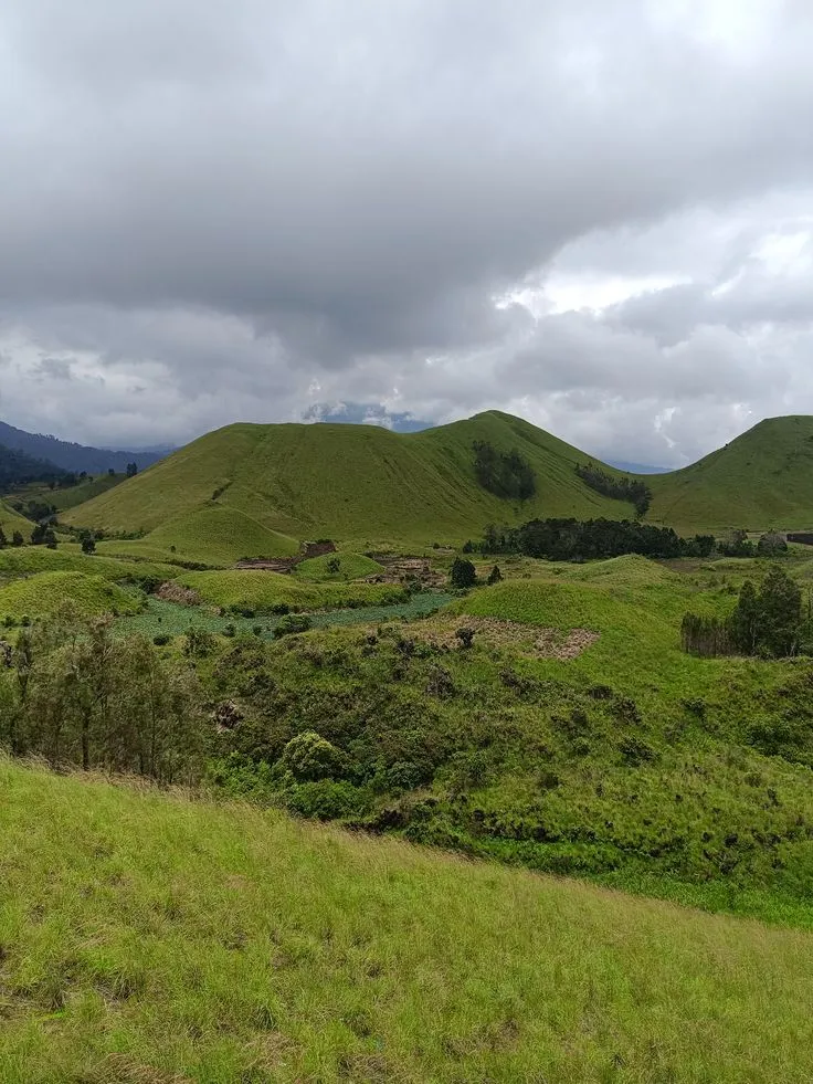 Perbukitan hijau Kawah Wurung di bawah langit berawan
