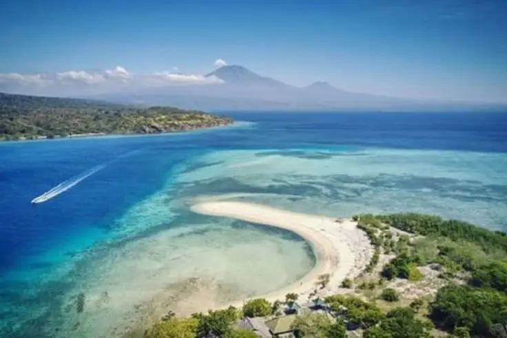 Foto udara pantai pasir putih dan perairan biru dengan terumbu karang